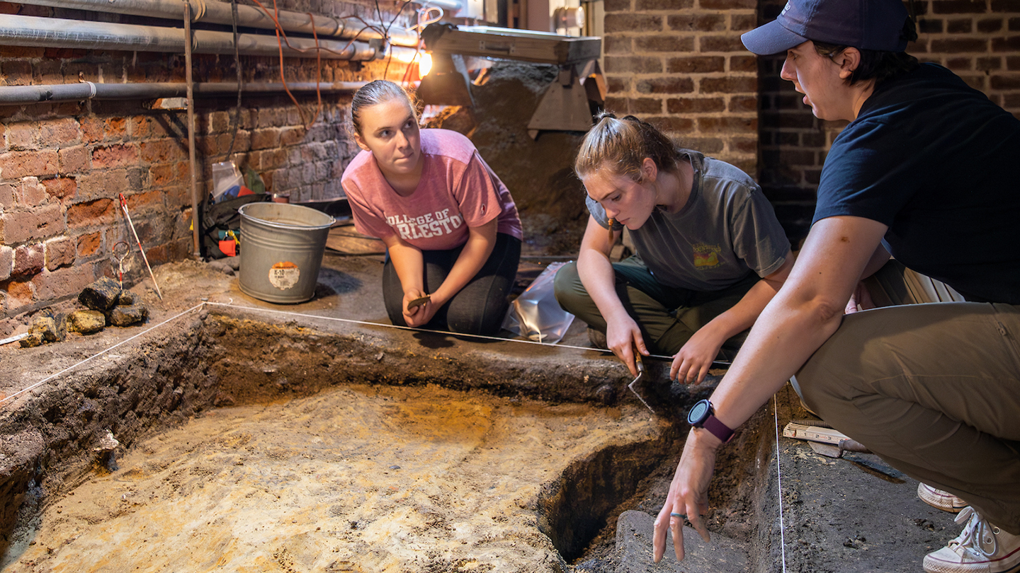 Three students conducting field research in archaeology.