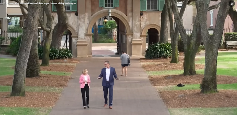Reporter and professor in conversation and walking along a brick pathway