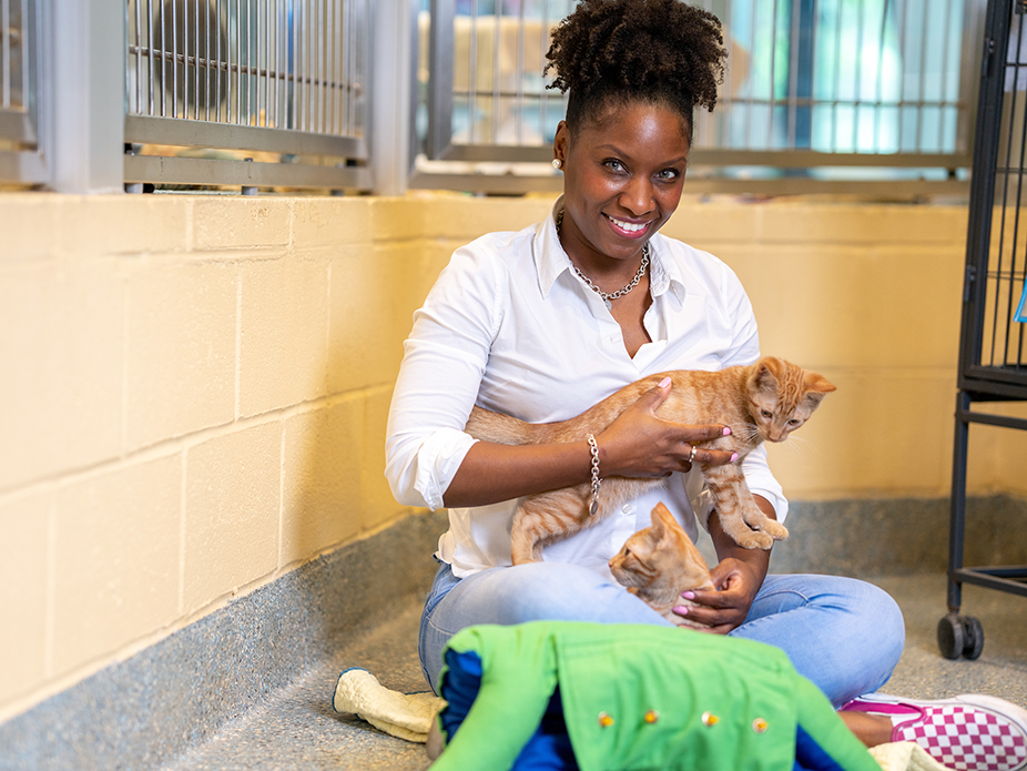 A woman sitting on the floor holding a kitten. 