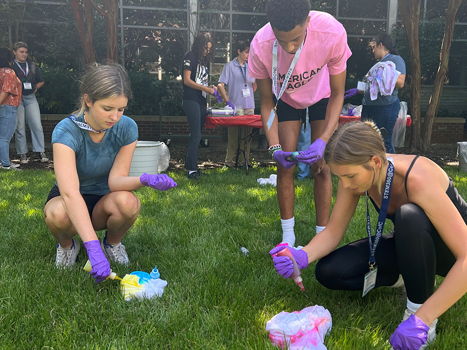 Three students conducting a chemistry experiment on grass.