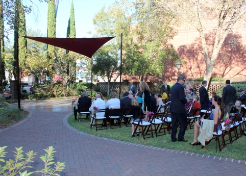 partially paved courtyard with people seated, watching event
