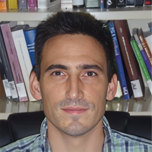 Headshot of Michael Gomez with a slight smile against a backdrop of textbooks on a bookshelf.