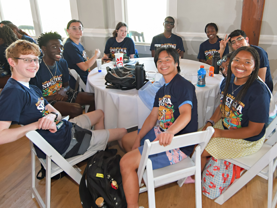 A diverse group of 10 SPECTRA participants smile at the camera while seated at a round table.