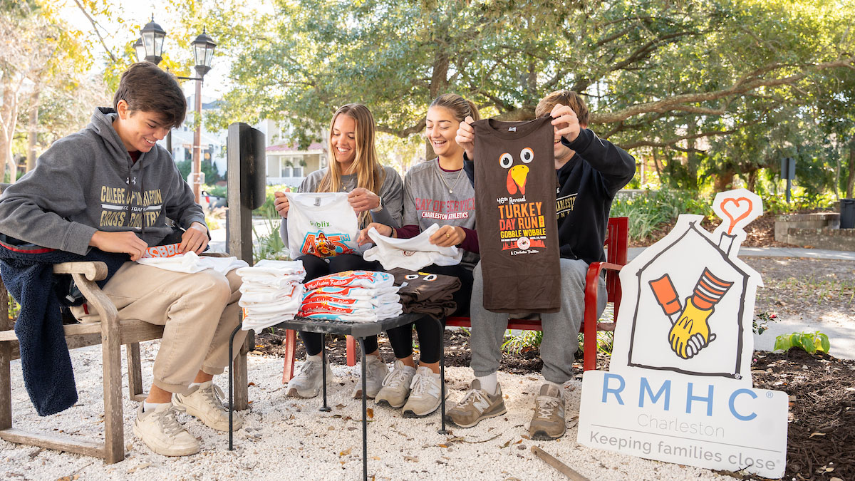 Four College of Charleston students folding t shirts as part of a volunteer experience.