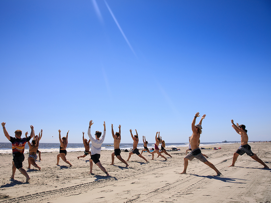 Group of College of Charleston students doing yoga at the beach. 