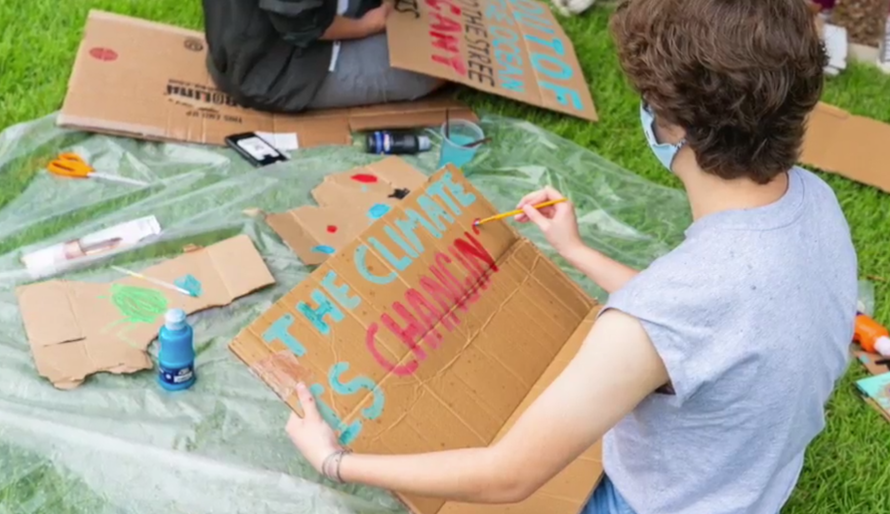 a student creating a sign at a climate change rally event