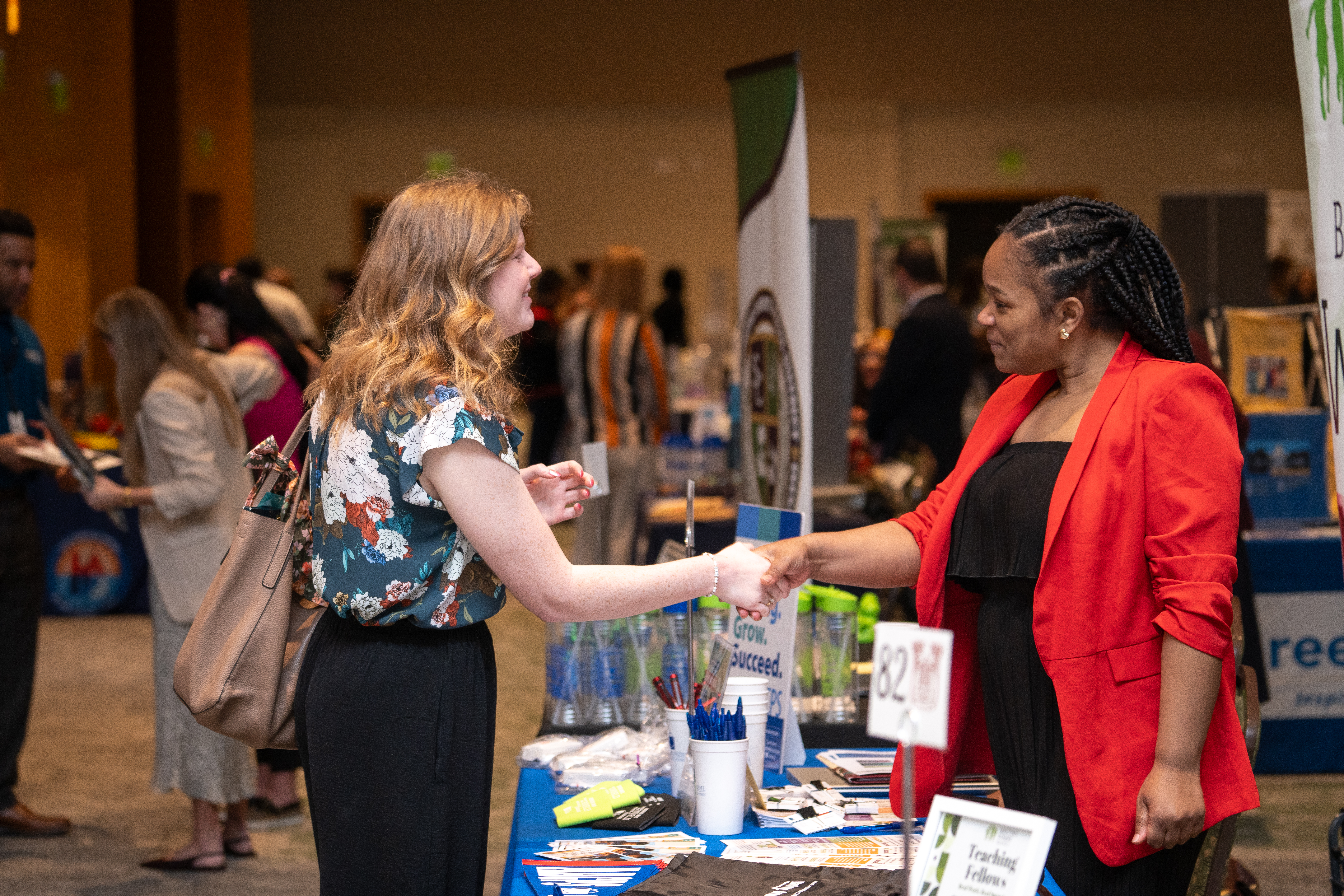Two adults shaking hands at a recruitment event.