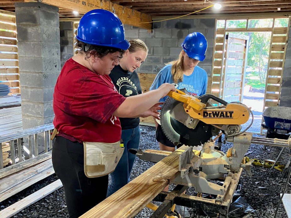 Student volunteers work the saw at a Habitat for Humanity build day.